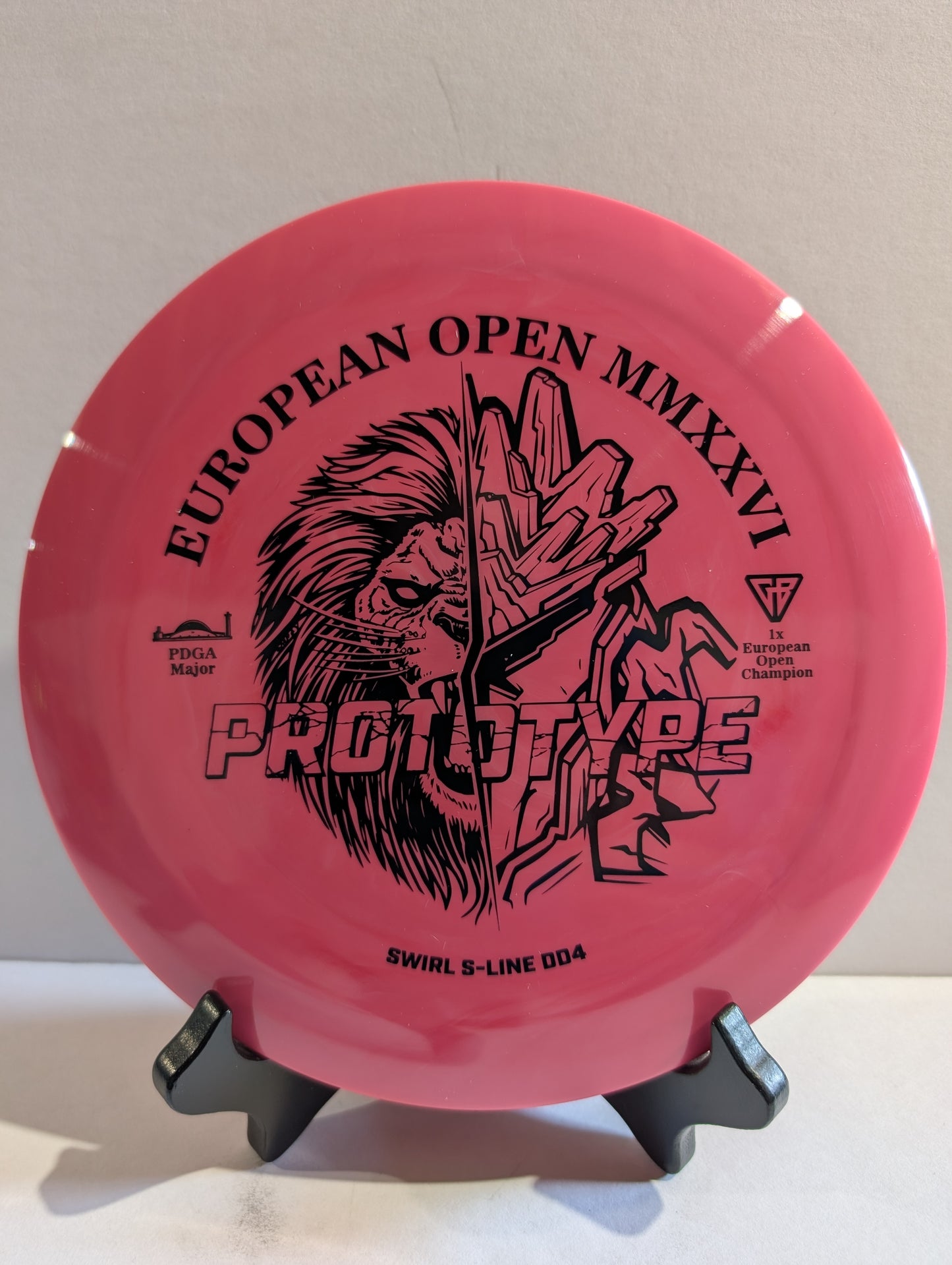 Pink disc with black graphics and text on a stand against a white background