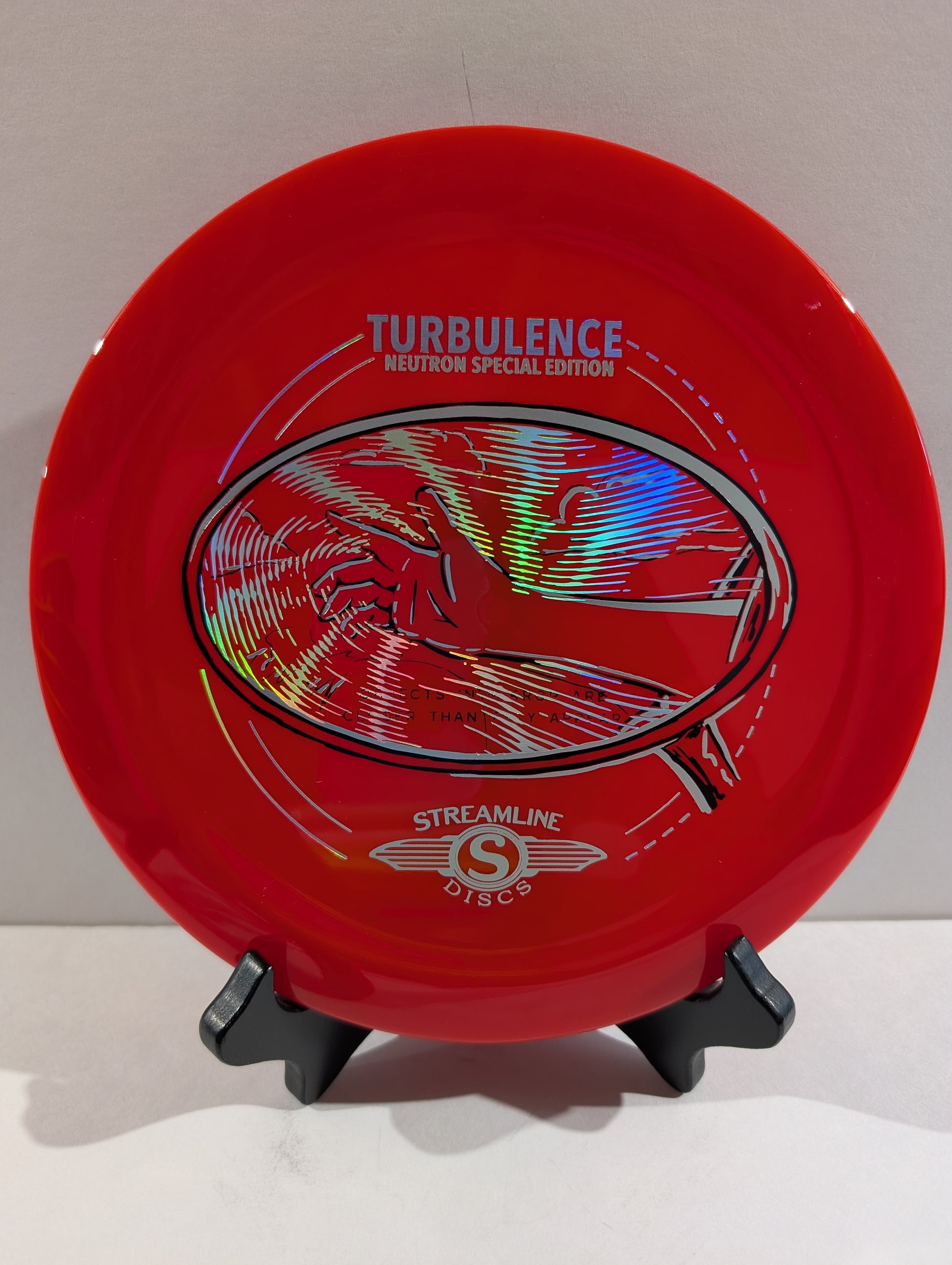 Red disc golf disc with 'Turbulence' and 'Streamline Discs' branding on a stand.