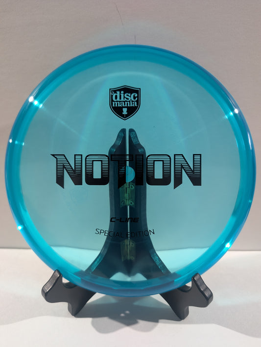 A translucent cyan blue disc golf disc with black printed graphics, displayed on a black stand against a neutral light gray background. The disc features the 'discmania' shield logo and the model name 'NOTION'.
