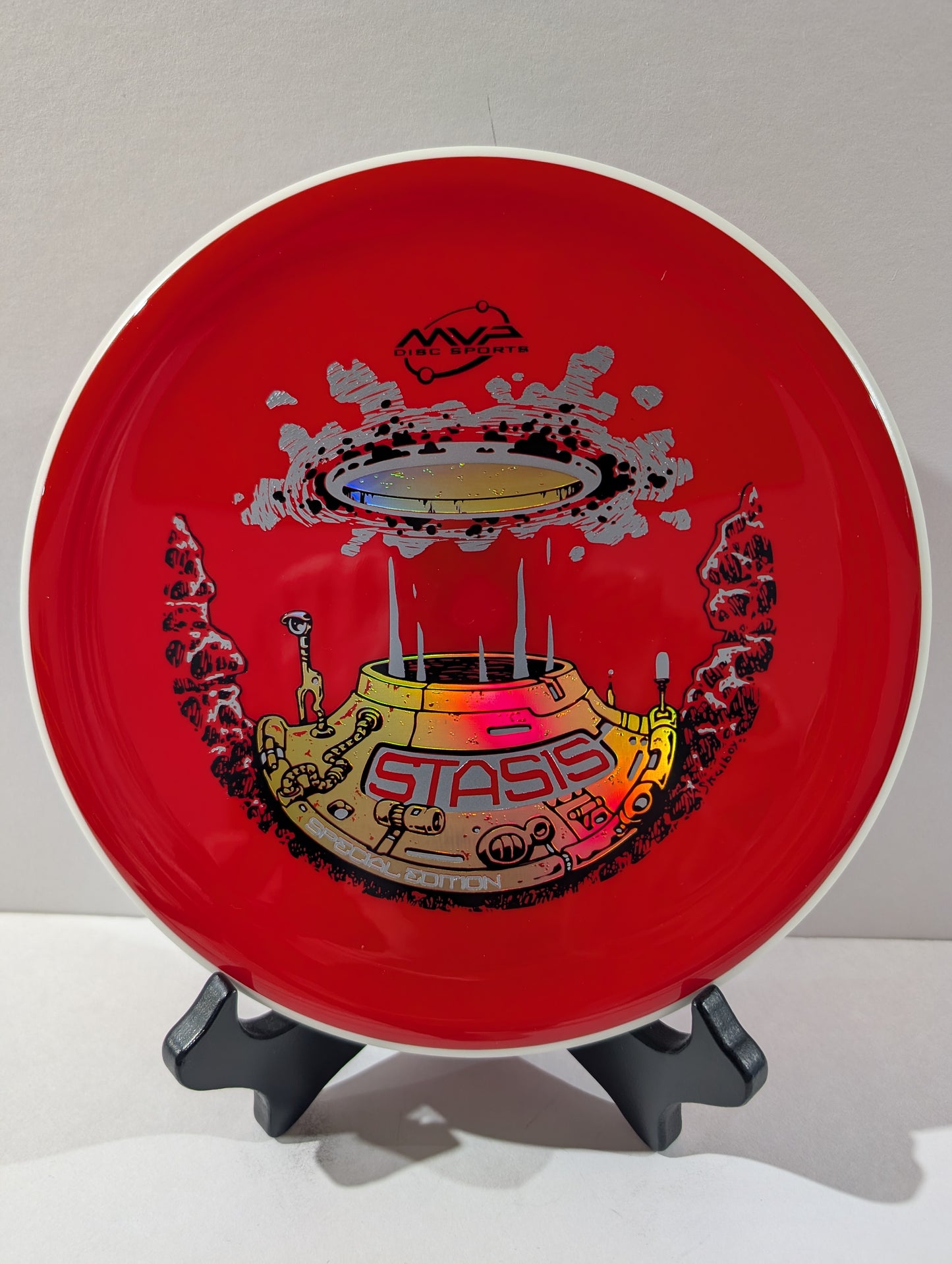Red disc with a colorful design on a stand against a white background