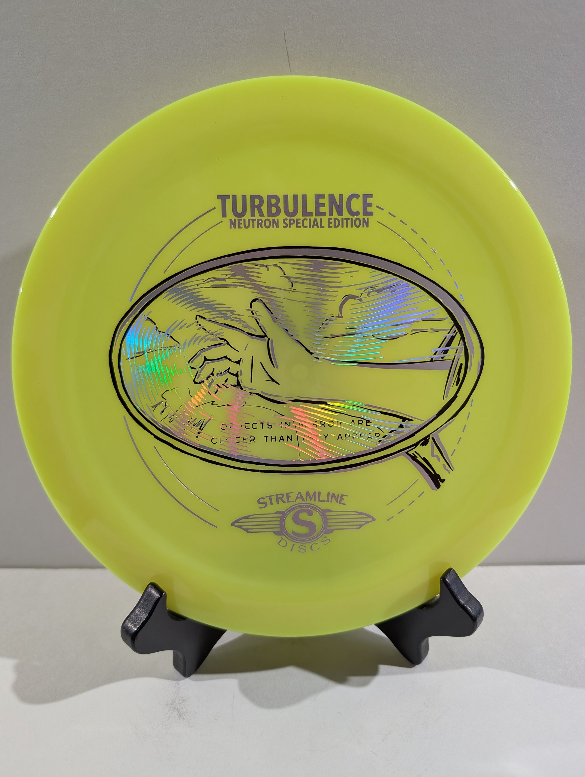 Yellow disc golf disc with branding on a stand against a white background