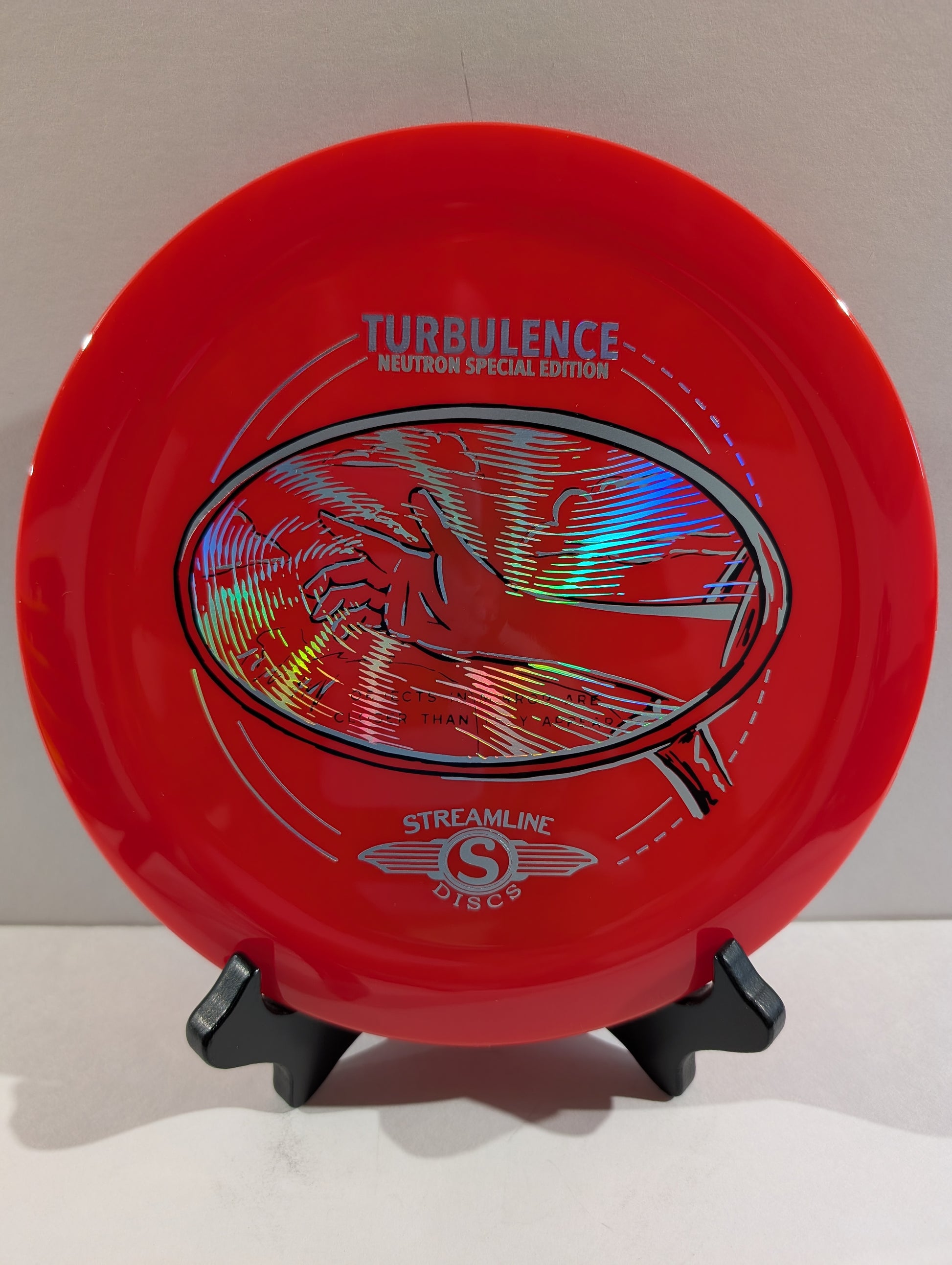 Red disc golf disc with branding on a stand against a white background