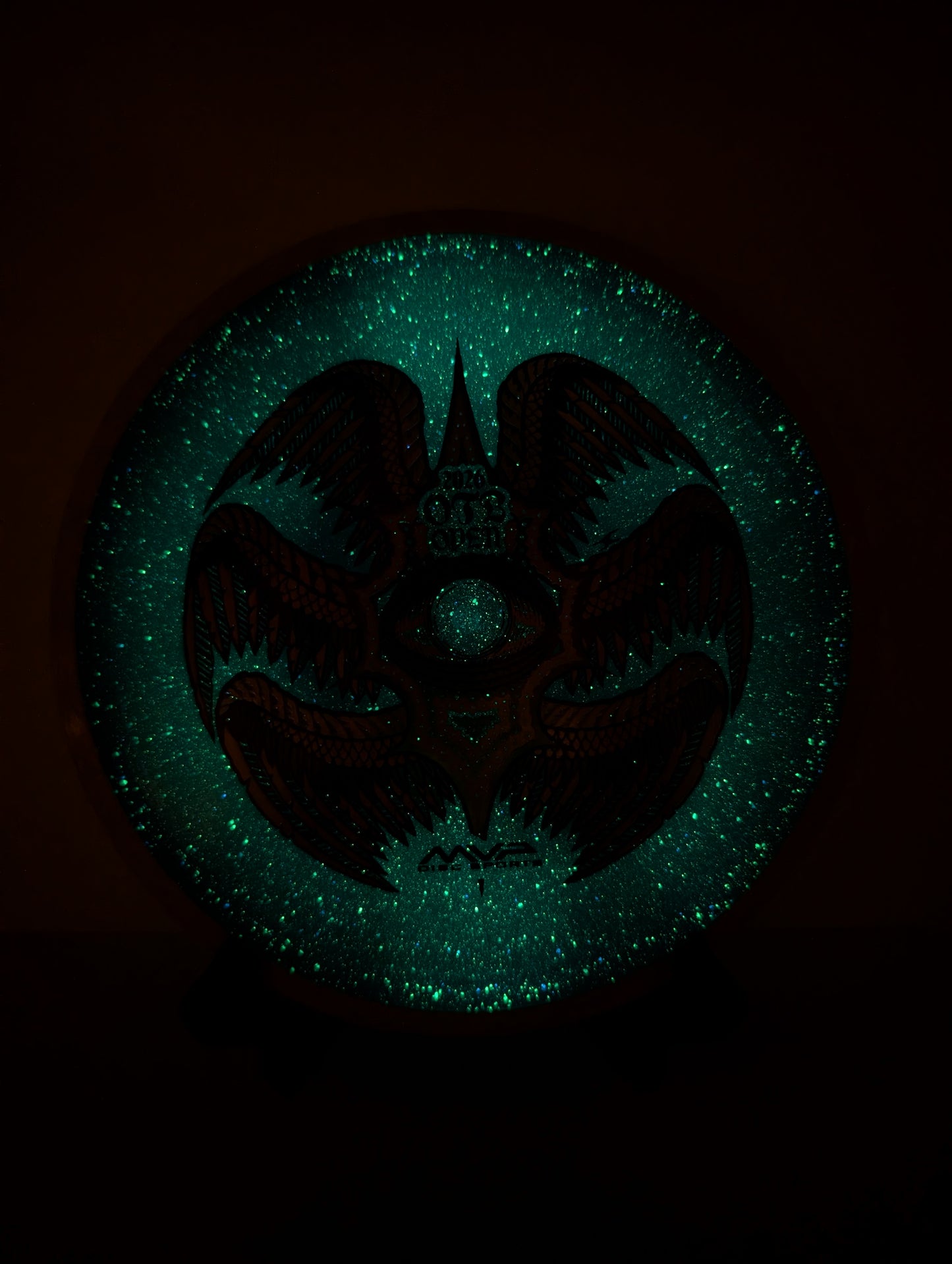 Glowing green emblem with a dark silhouette on a black background