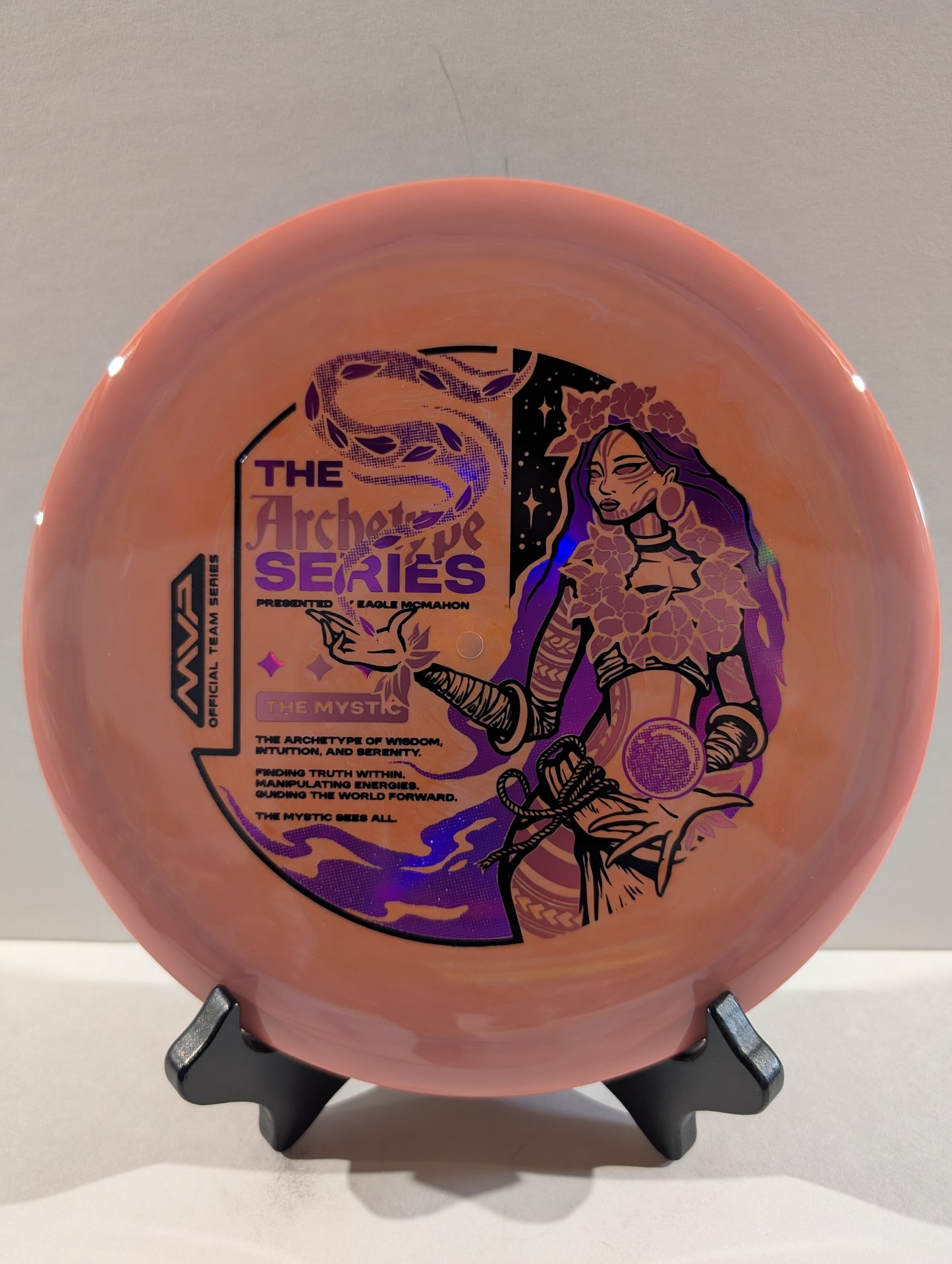 Pink disc with black and purple graphics on a stand against a gray background