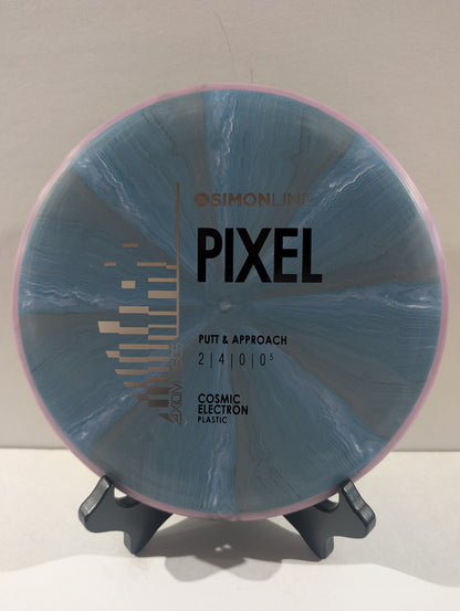 A disc golf disc on a small display stand, featuring a blue and gray marbled pattern with a pink outer rim. The disc is branded with 'Simon Line' and 'Pixel'.