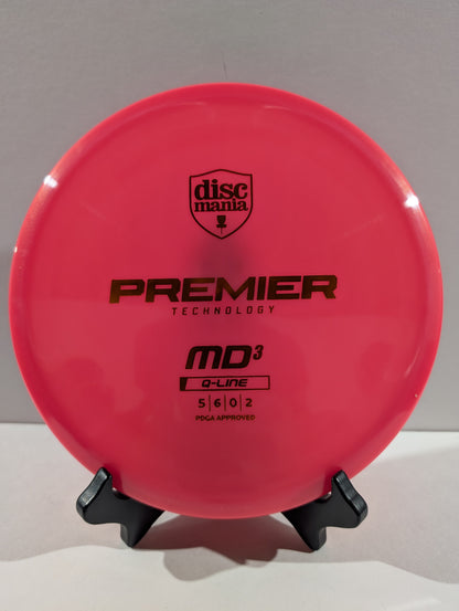 A bright pink Discmania Premier Technology MD3 Q-Line disc golf disc displayed on a small black stand against a neutral gray background.