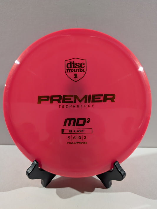 A bright pink Discmania Premier Technology MD3 Q-Line disc golf disc displayed on a small black stand against a neutral gray background.