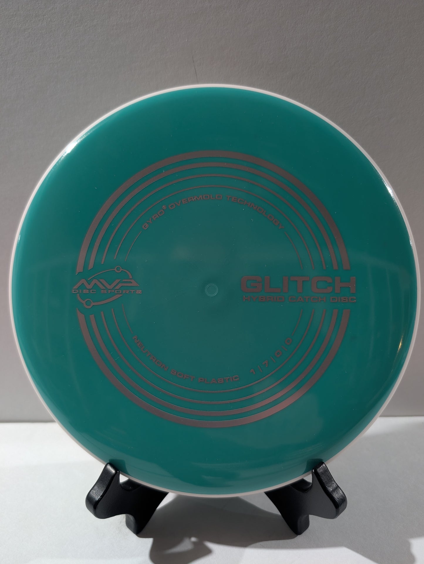 Teal disc with 'Glitch' branding on a stand against a gray background