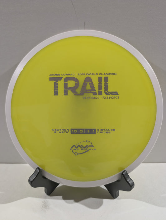 Disc golf disc with 'Trail' branding on a stand against a white background