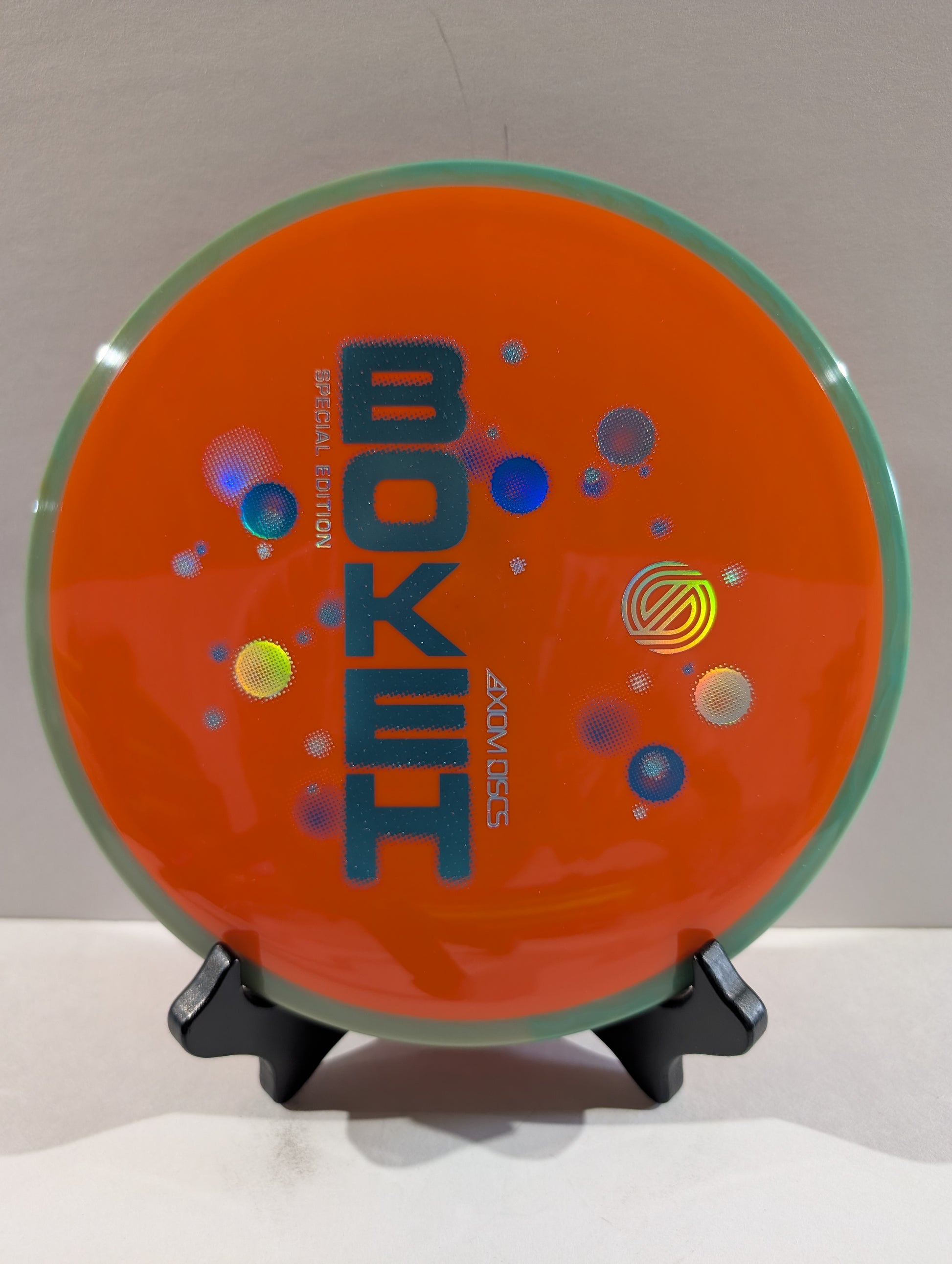 Orange disc with 'Bokeh' branding on a stand against a neutral background