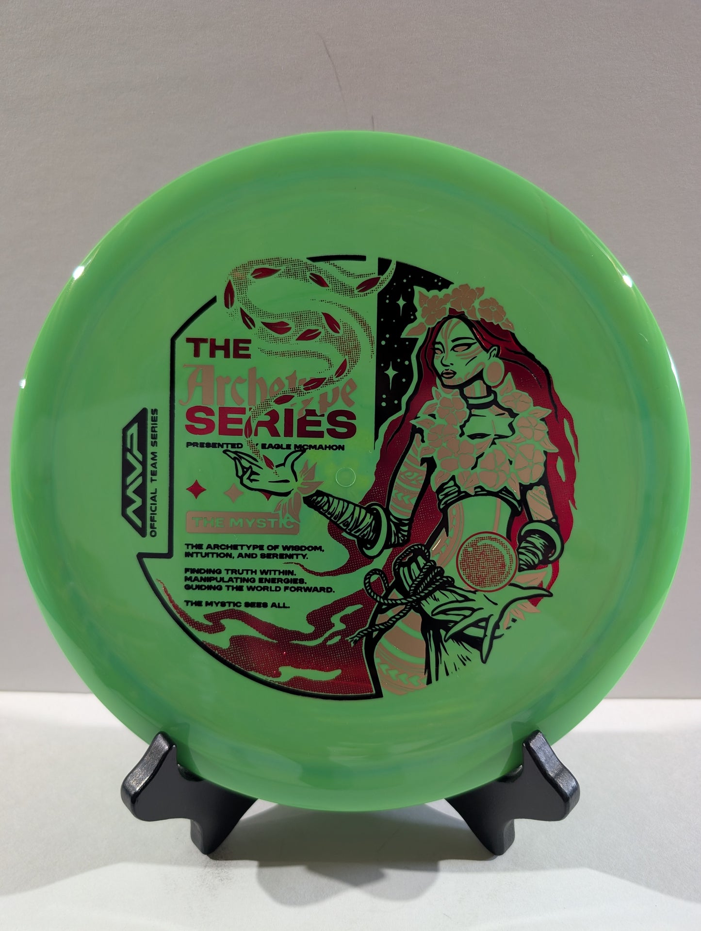 Green disc with artistic design and text on a stand against a neutral background