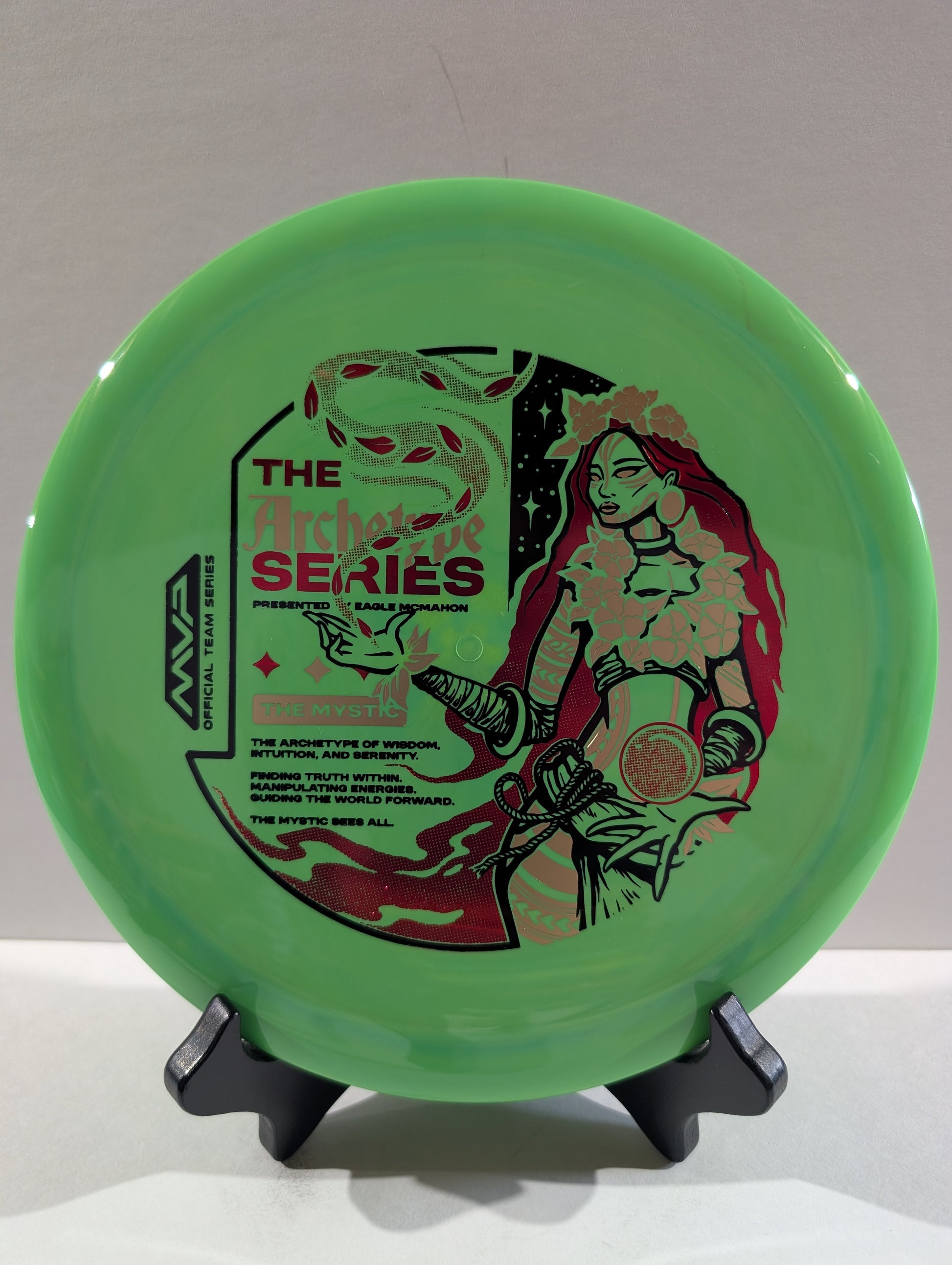Green disc with artistic design and text on a stand against a neutral background