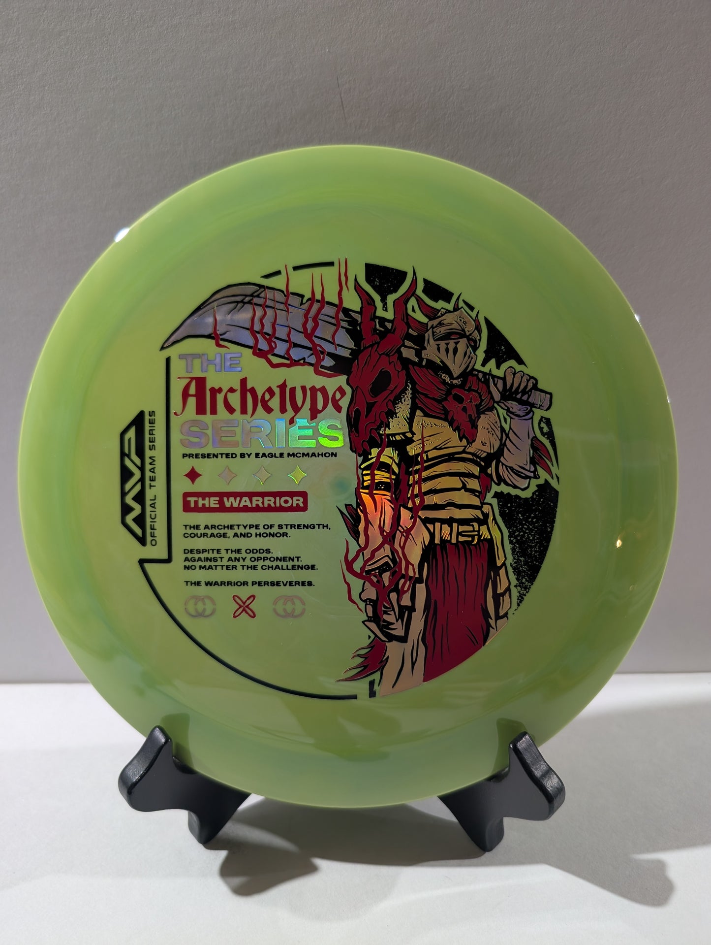 Green disc with 'The Archetype Series' and 'The Warrior' branding on a stand against a gray background.