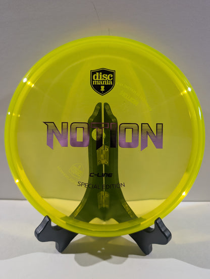 A translucent neon yellow Discmania Notion C-Line Special Edition disc golf disc displayed on a black stand against a neutral gray background.
