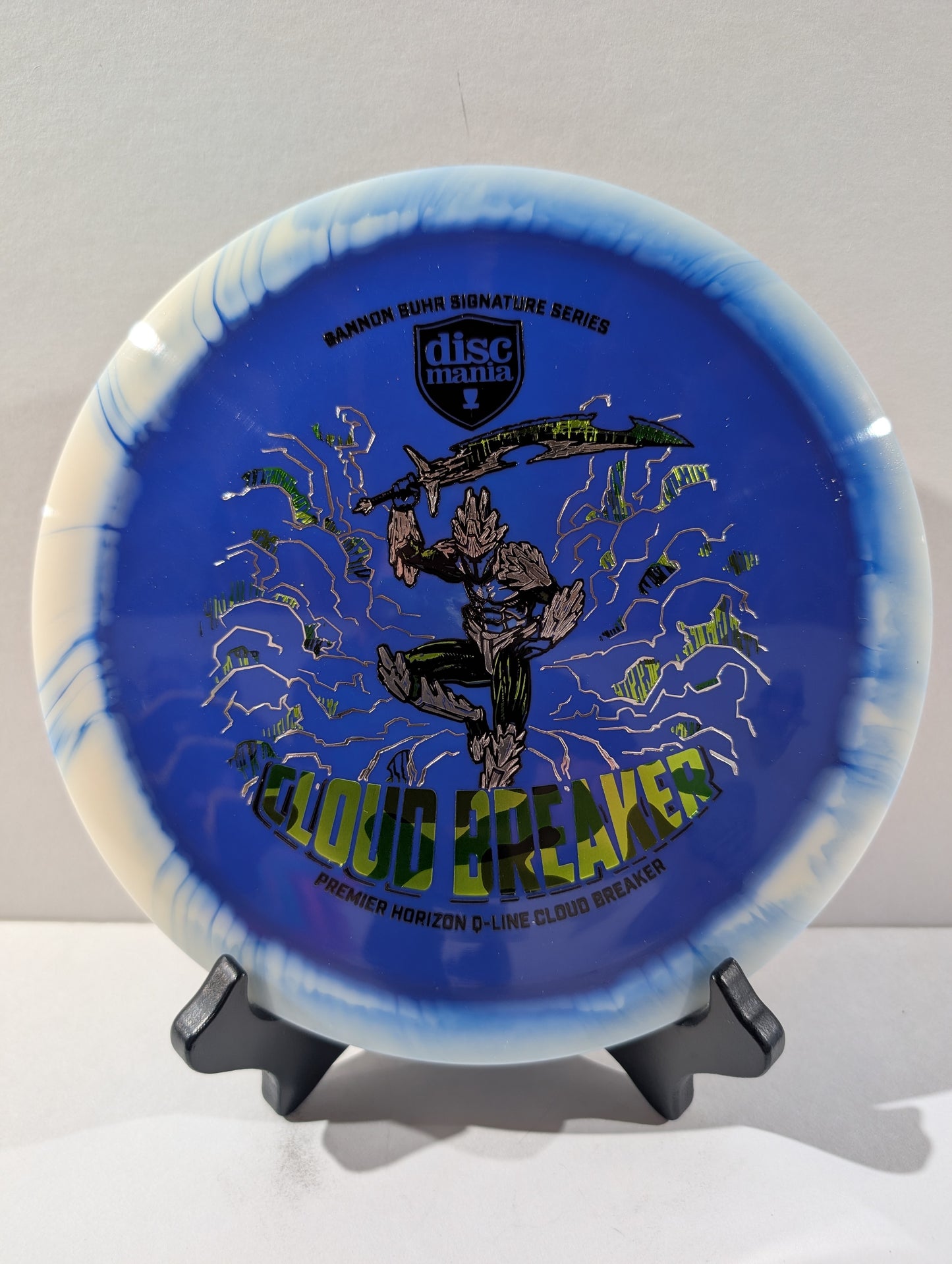 Blue and white disc with 'Discmania' branding and graphics on a stand against a light gray background