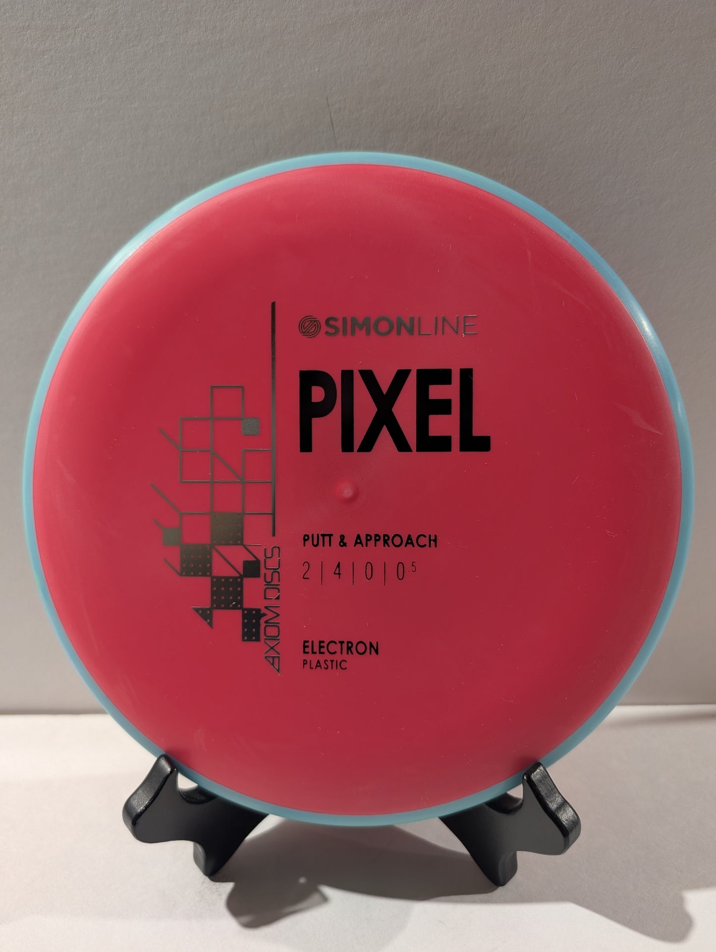 Red and blue disc golf disc with 'Simonline Pixel' branding on a stand.