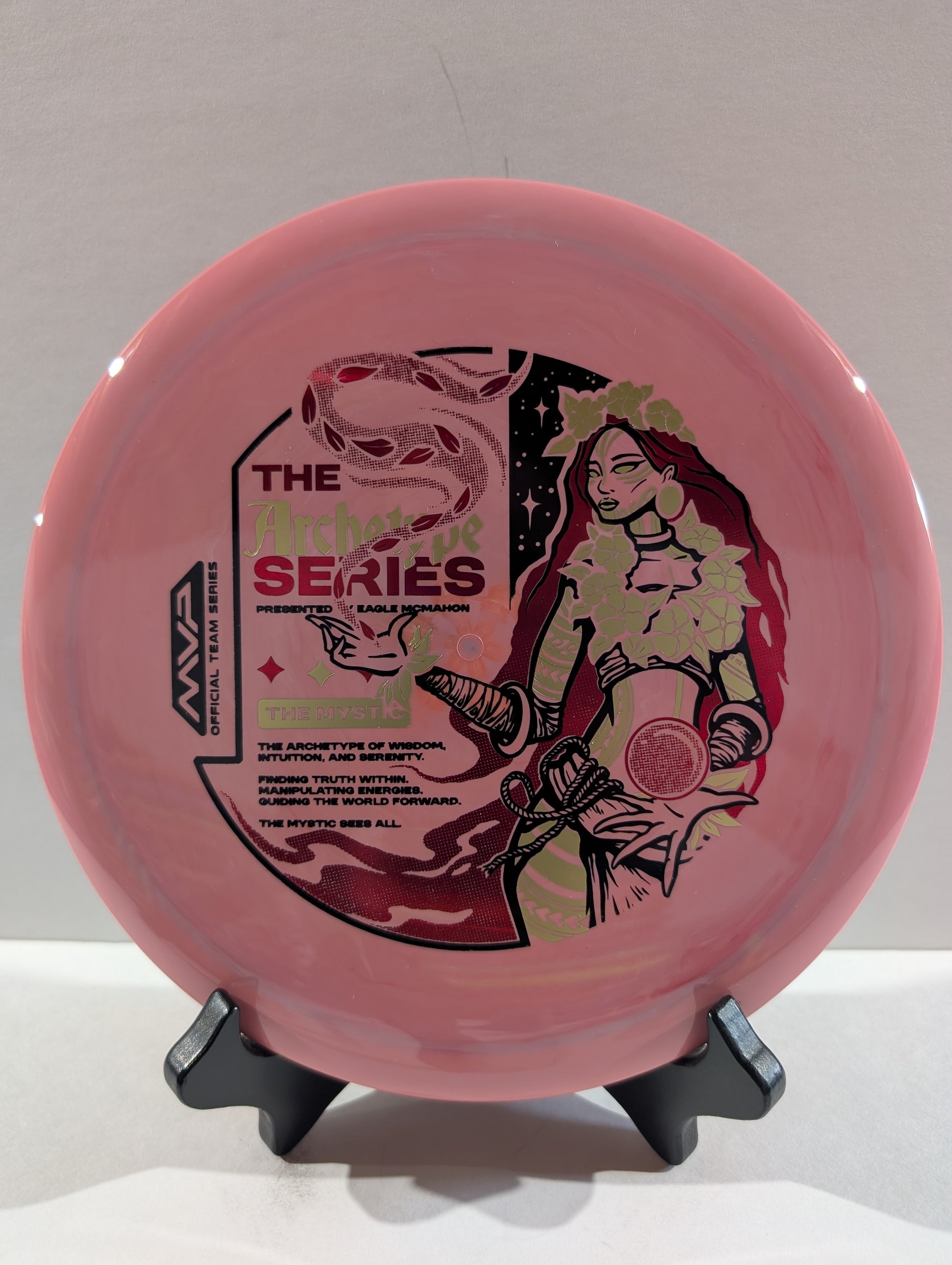 Pink disc with graphic design on a stand against a gray background