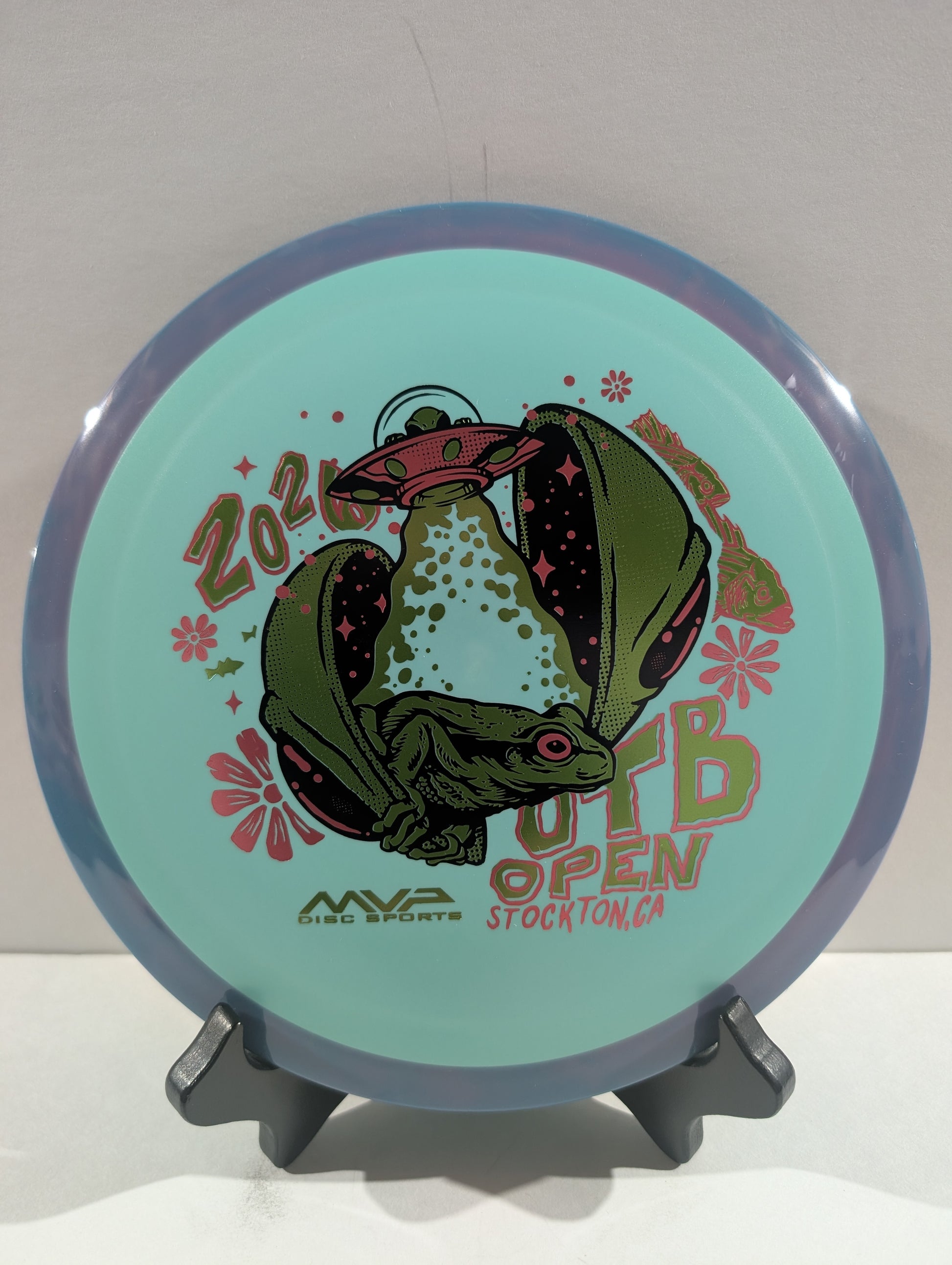 Disc with alien design and text on a stand against a white background
