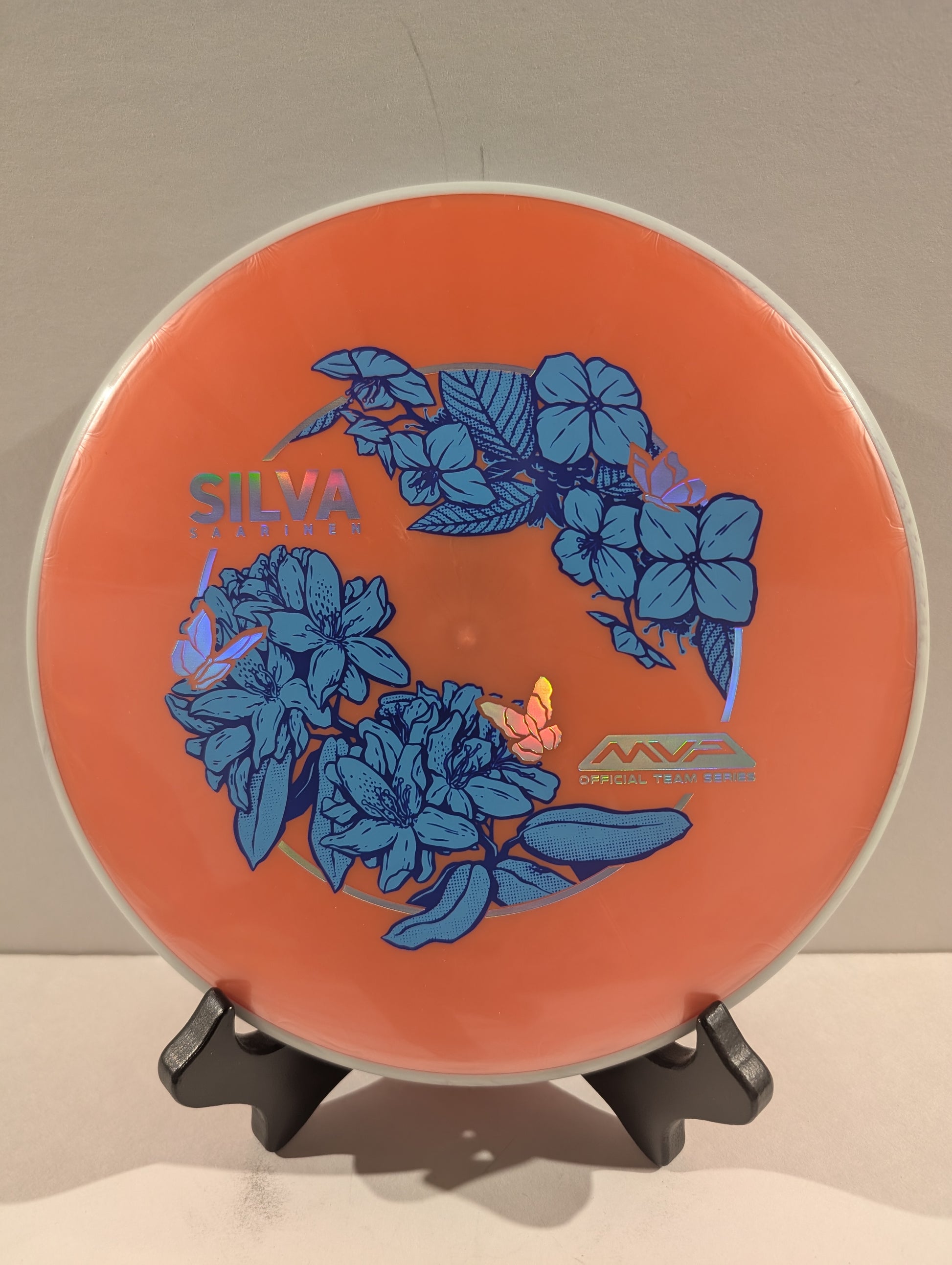 Orange disc with blue floral design and 'Silva' branding on a stand.
