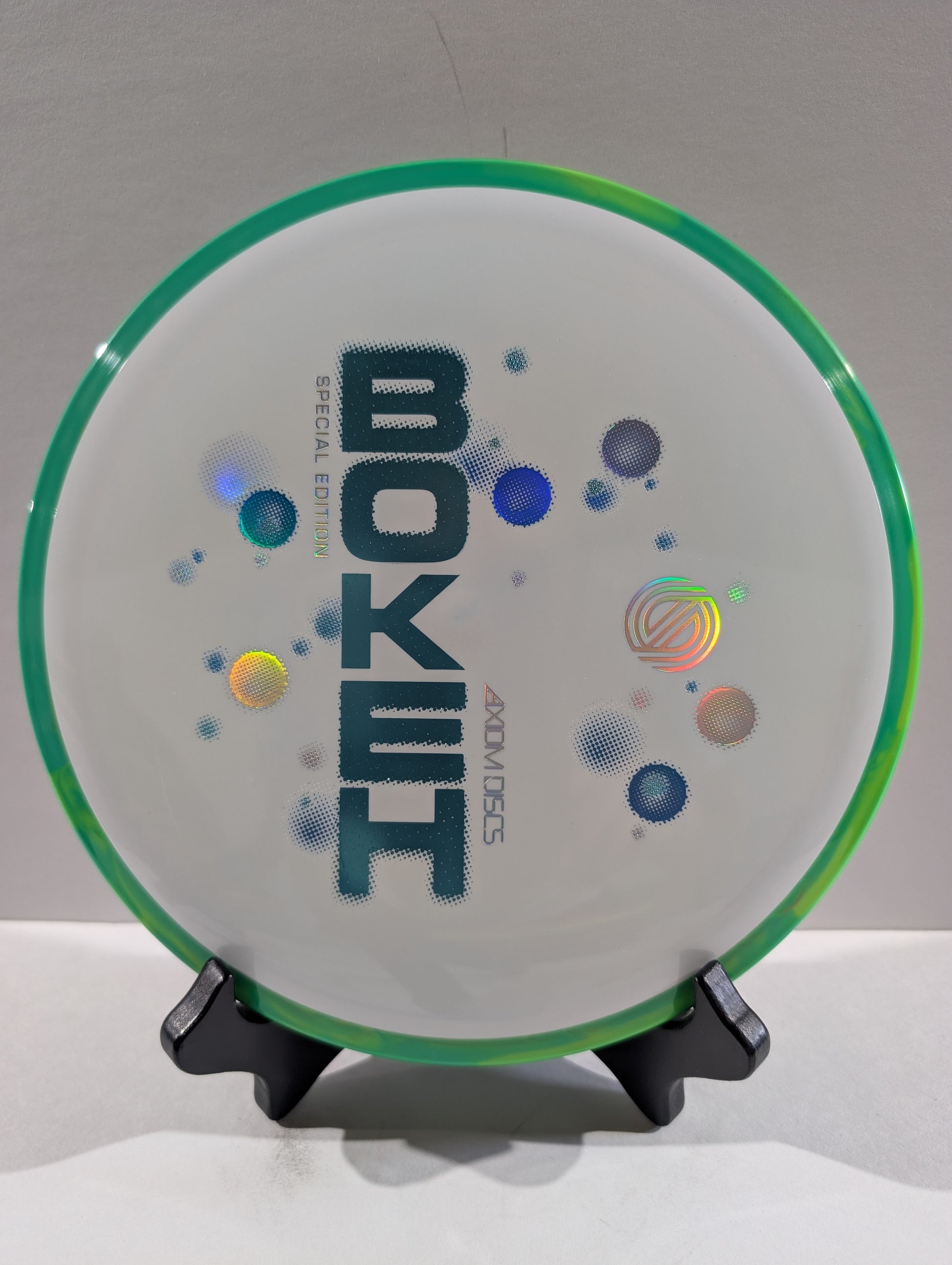 White disc golf disc with 'Bokeh' branding on a stand against a gray background