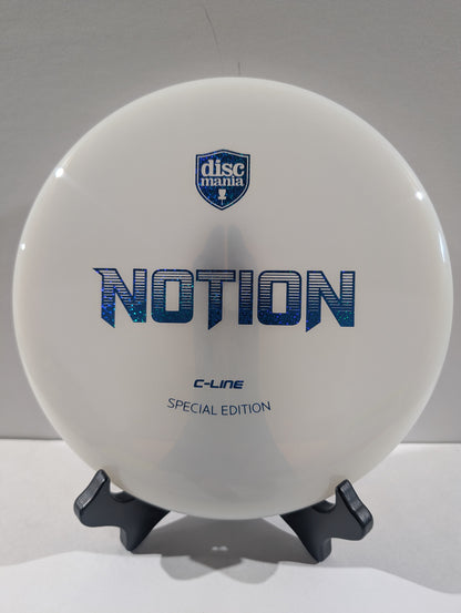 A white Discmania Notion C-Line Special Edition disc golf disc displayed on a black stand against a neutral gray background.