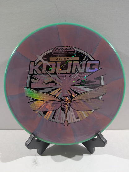 Disc golf disc with a dragonfly design and branding on a stand against a white background