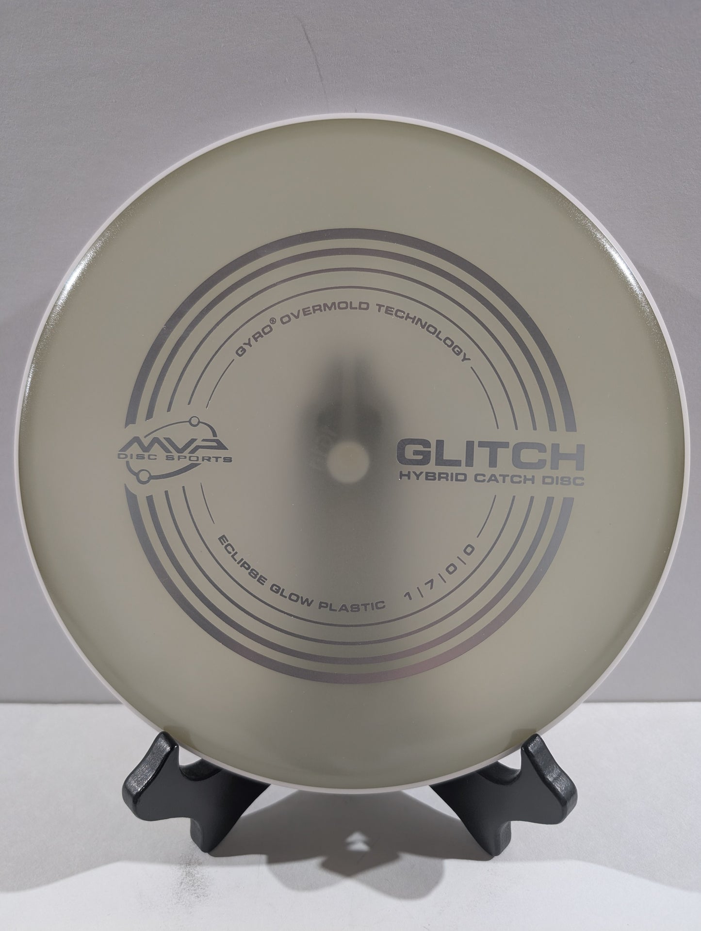 Disc golf disc with 'Glitch' branding on a stand against a gray background