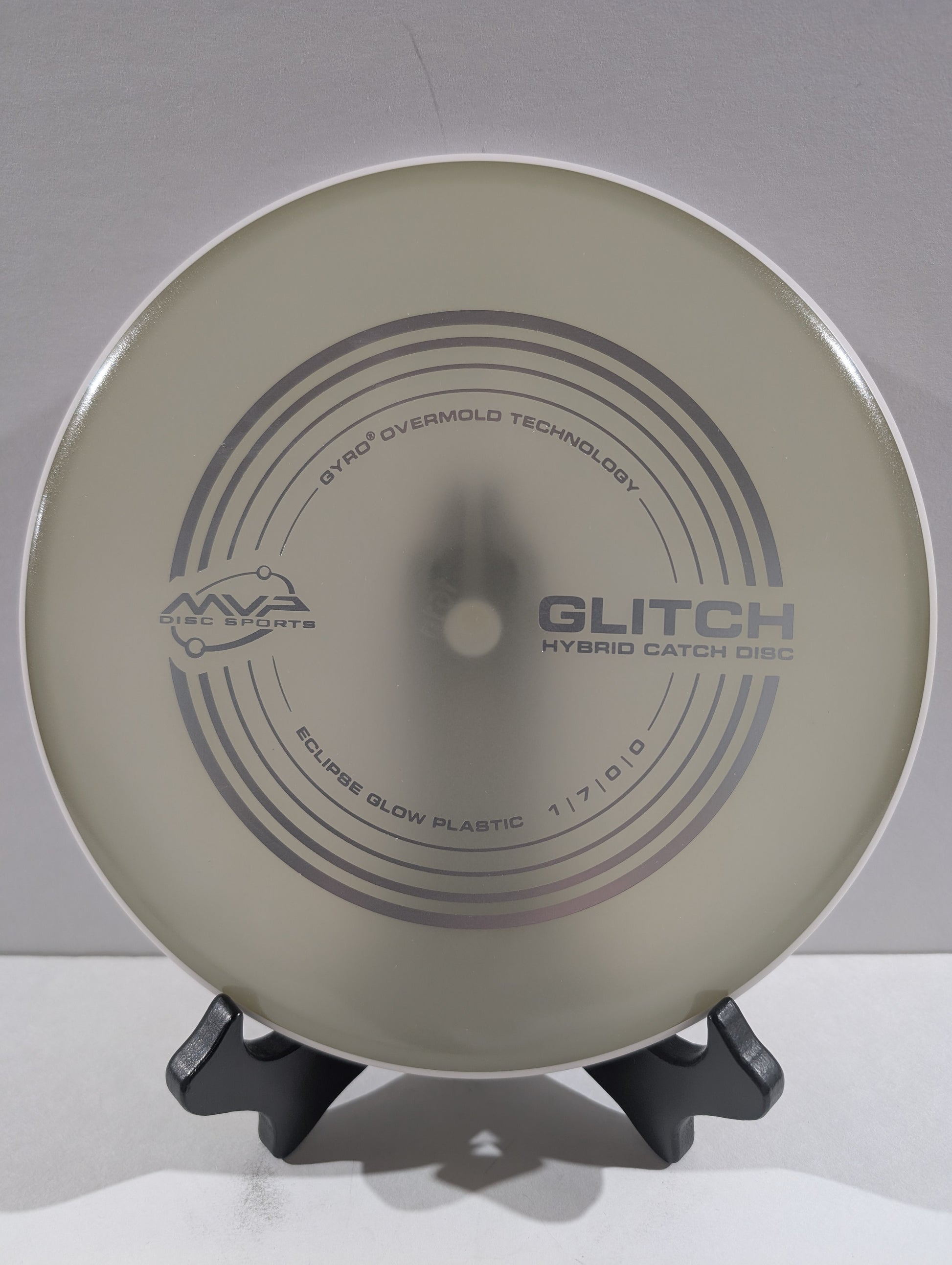 Disc golf disc with 'Glitch' branding on a stand against a gray background