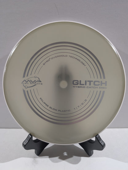 Disc golf disc with 'Glitch' branding on a stand against a gray background