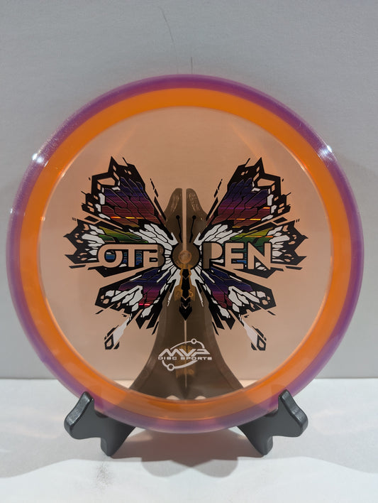 Disc golf disc with butterfly design and 'OTB Open' branding on a stand against a white background