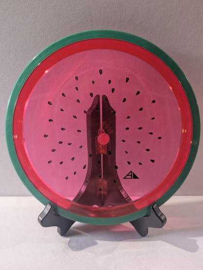 Watermelon disc colored like a watermelon with a stand on a plain background