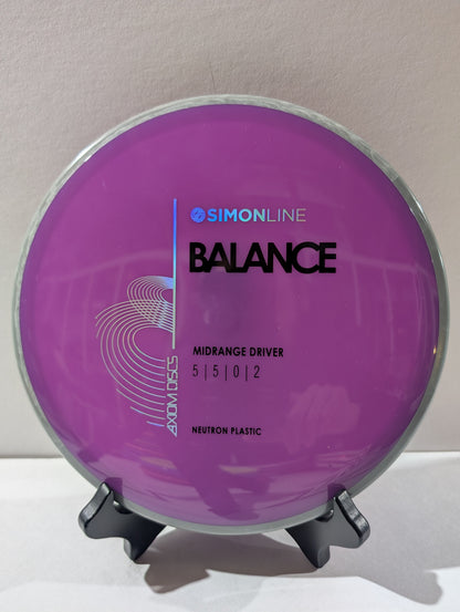 Purple disc golf disc with 'Simonline Balance' branding on a stand against a neutral background