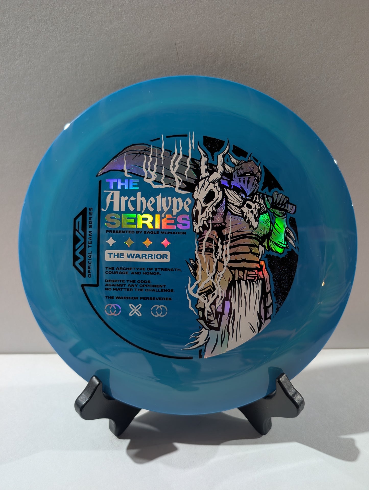 Blue disc with 'The Archetype Series' and 'The Warrior' design on a stand against a gray background