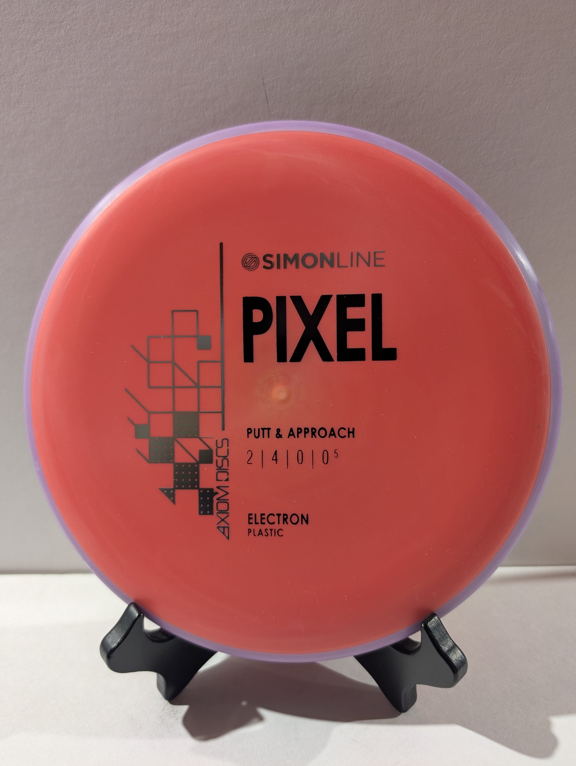Red disc golf putter with 'Simonline Pixel' branding on a stand.