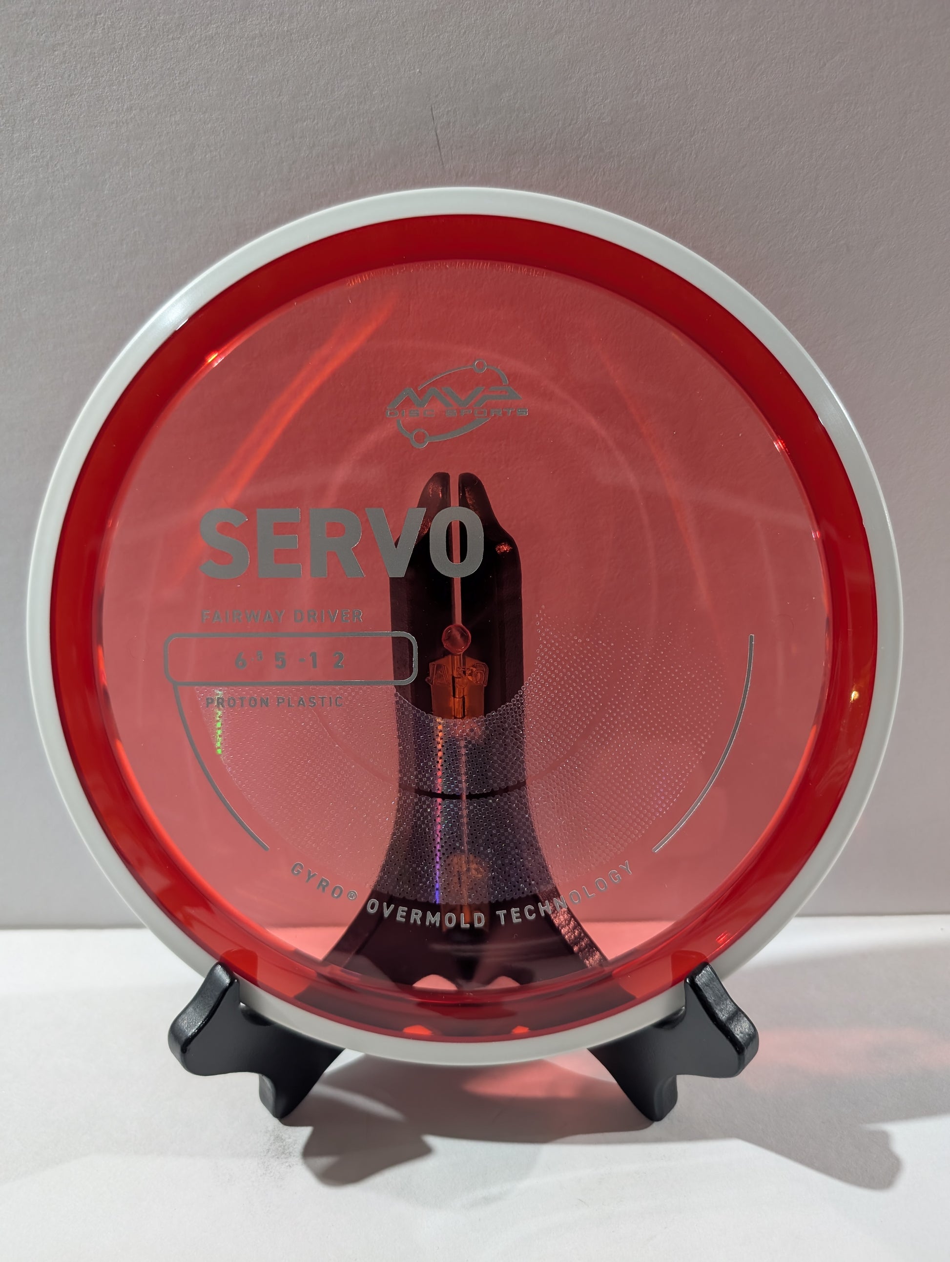 Disc golf disc with 'Servo' branding on a stand against a gray background