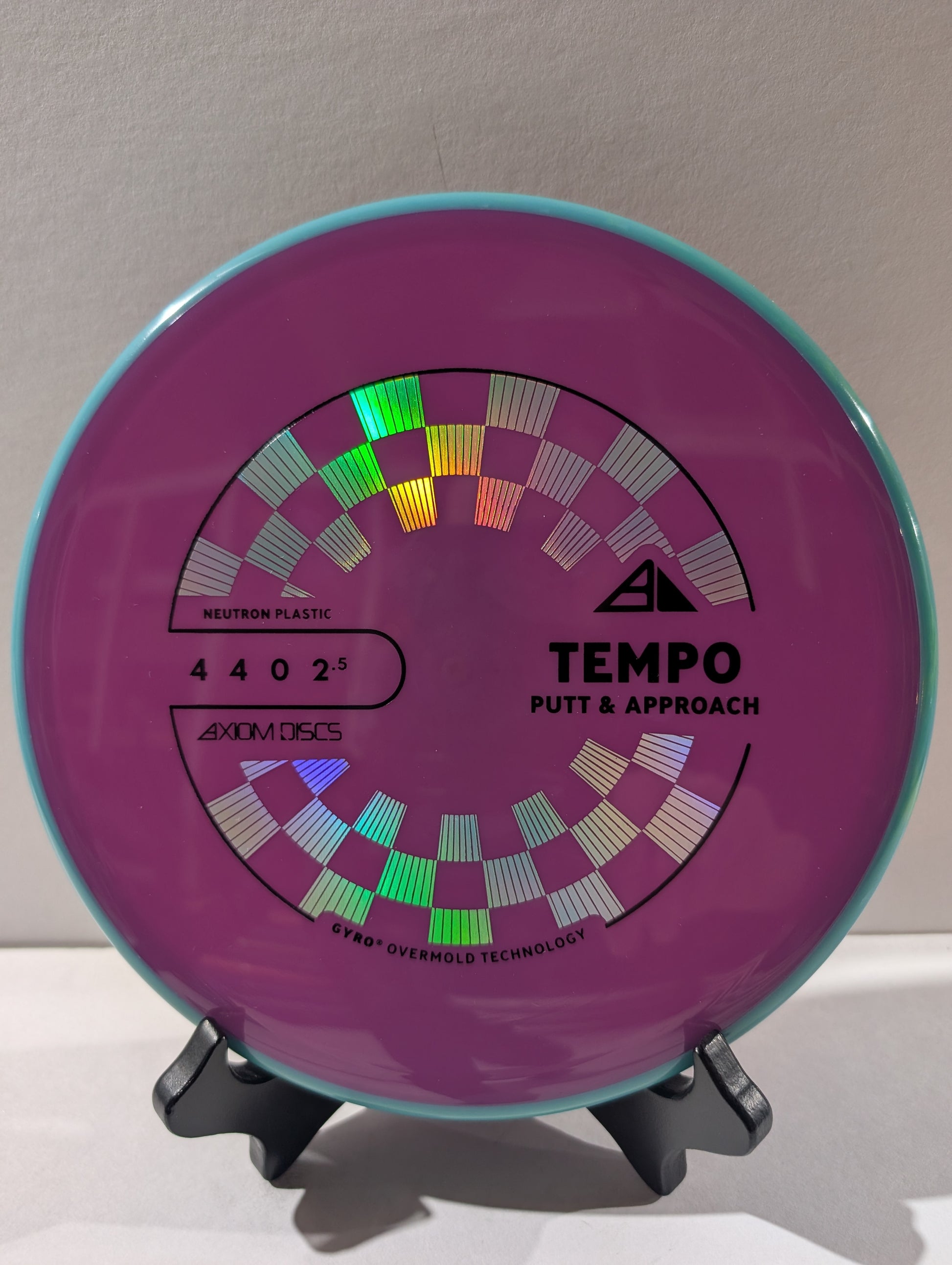 Purple and blue disc golf putter with 'Tempo' branding on a stand.