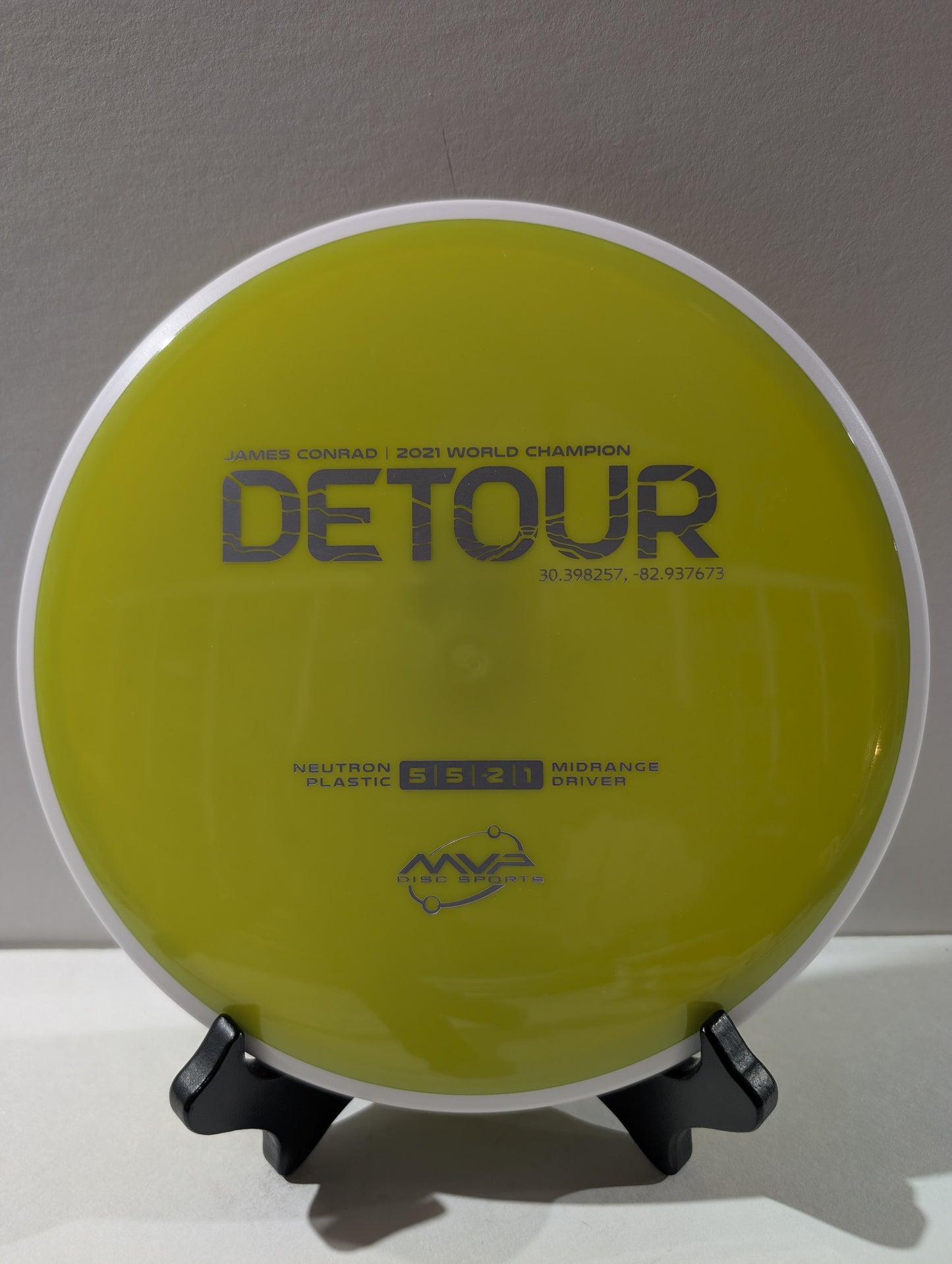 Disc golf disc with 'Detour' branding on a stand against a gray background