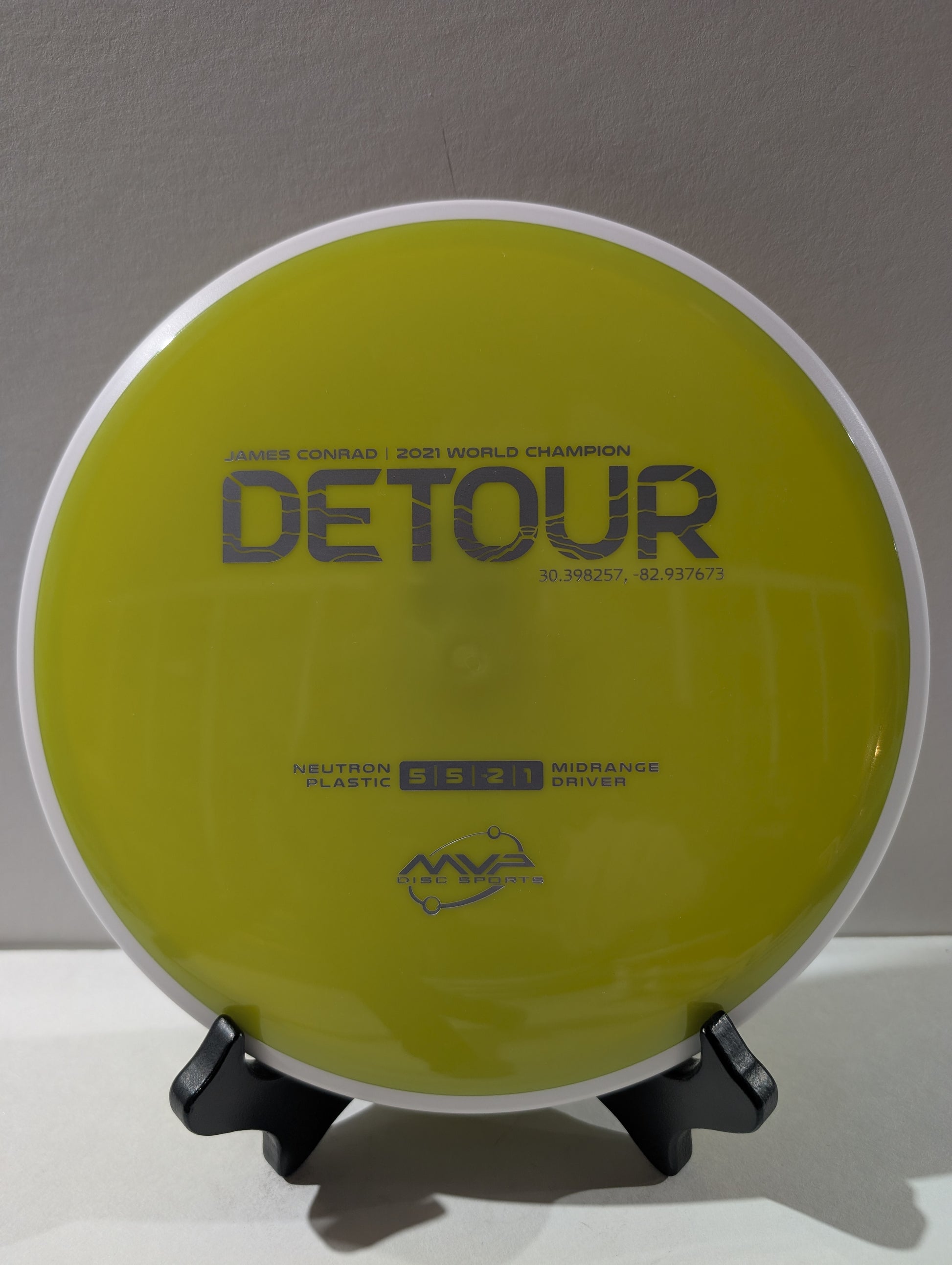Disc golf disc with 'Detour' branding on a stand against a gray background