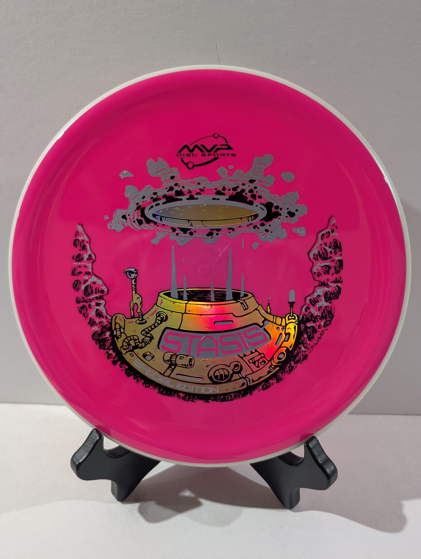 Pink disc with a colorful design on a stand against a gray background