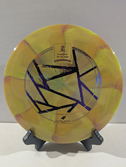 A yellow disc golf disc with a purple geometric star design and a gold 'Foundation for St. Jude' patch, displayed on a small black stand against a light gray background.