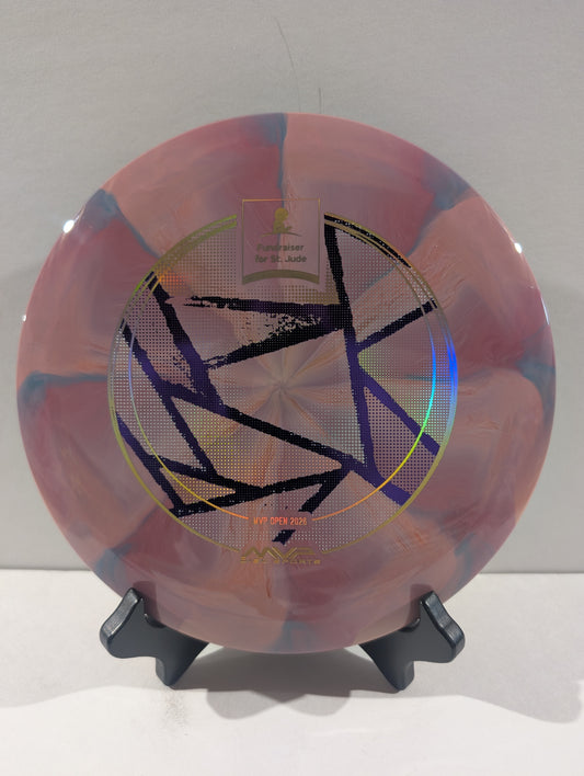 A disc golf disc with a pink, purple, and blue marbled pattern, featuring a black geometric star design and foil stamp in the center, displayed on a black stand against a neutral gray background.