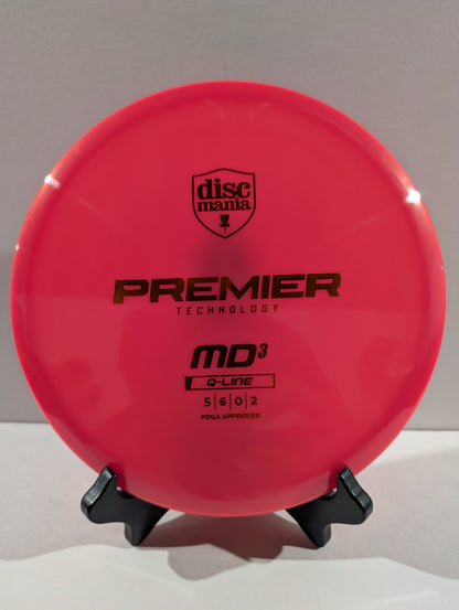 A bright pink Discmania Premier Technology MD3 disc golf disc displayed on a small black stand against a neutral gray background.