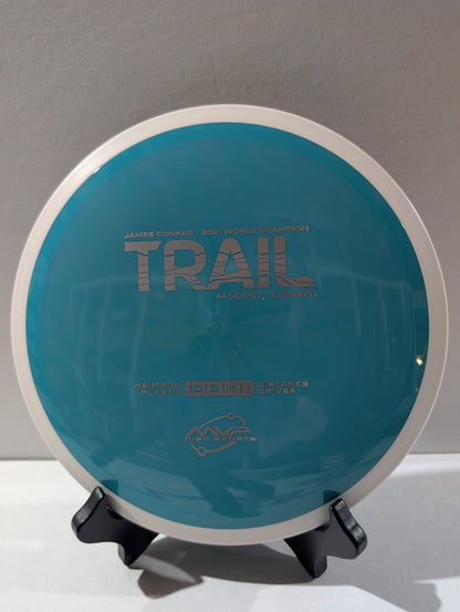 Teal disc golf disc with 'Trail' branding on a neutral background