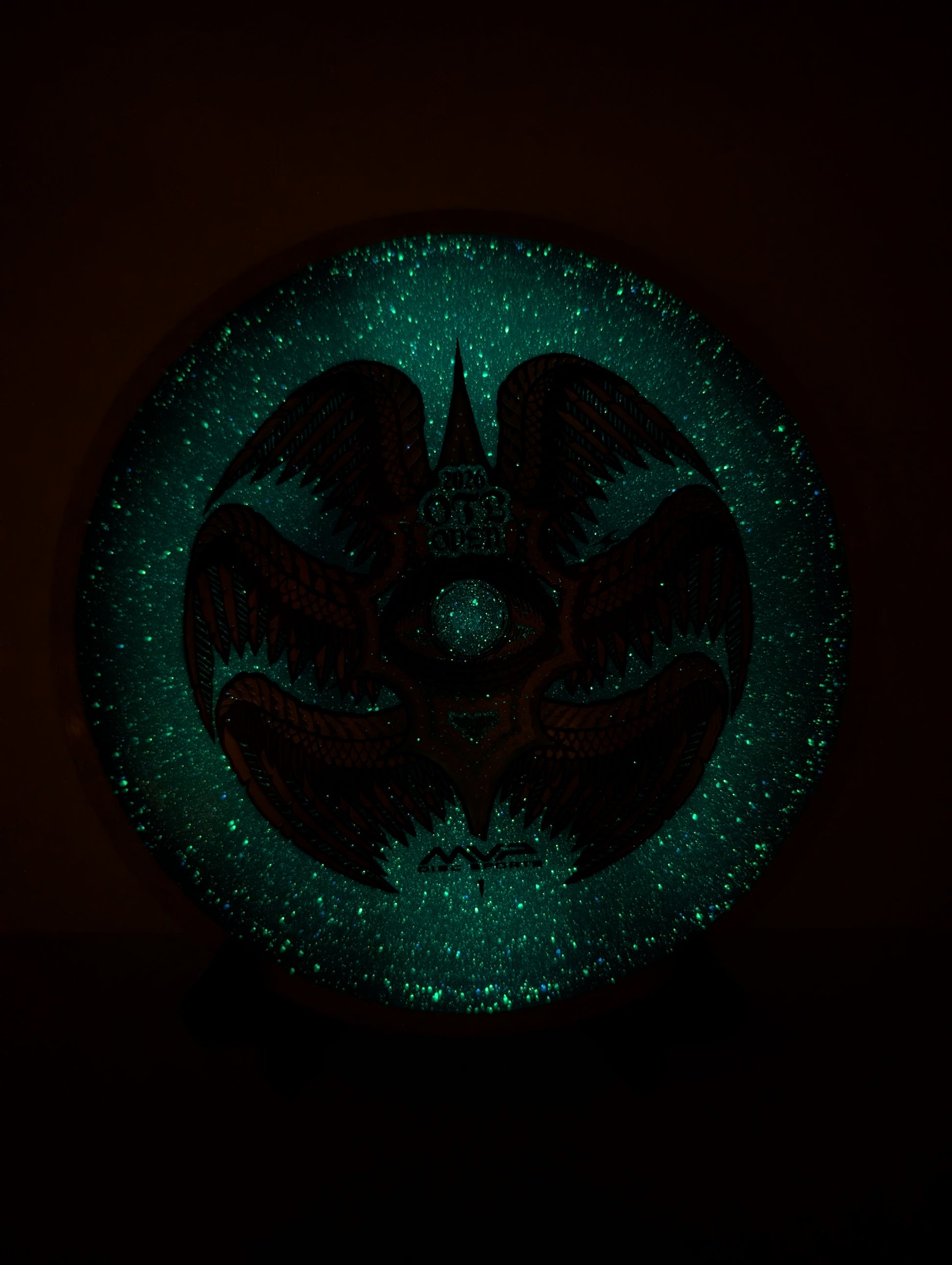 Glowing green emblem with a dark silhouette on a black background