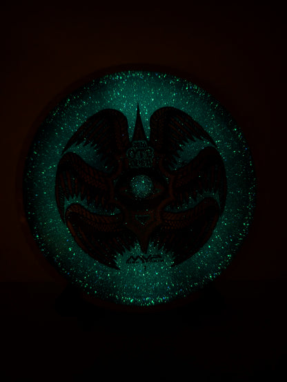 Glowing green emblem with a dark silhouette on a black background
